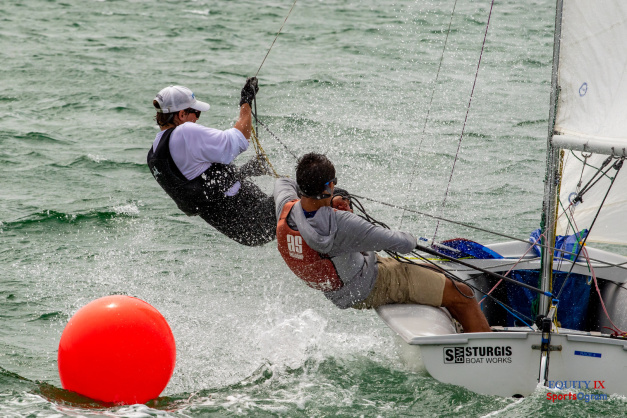 tow boys are sailing a 420 in rough water rounding a red marker in a race with spray coming off the ocean as they pull on ropes own the sailboat © Equity IX - SportsOgram - Leigh Ernst Friestedt